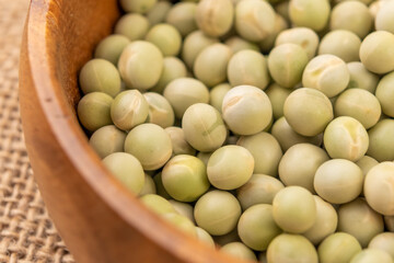 Dry green peas. Dried hard legumes in wooden bowl on rustic sackcloth