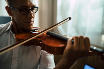 Close up scene of musician practicing violin in the music instrument room.