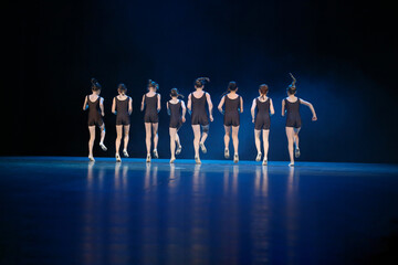 Girls dance on stage. They run forward together.