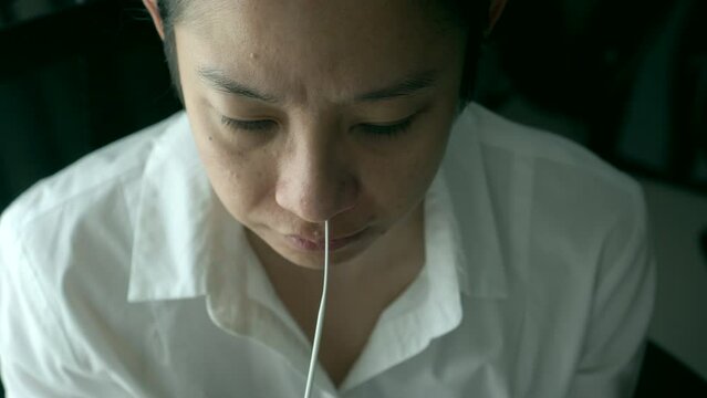 Asian woman doing self test ATK nasal swap from her nose for covid-19