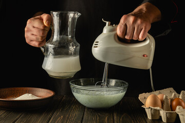The chef uses a hand-held electric mixer to prepare a delicious breakfast or lunch with eggs and milk. Menu idea for a restaurant or hotel