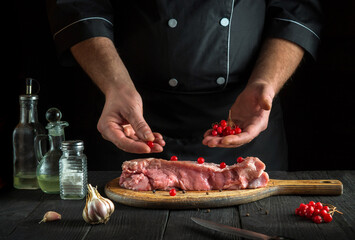 In the kitchen chef prepares raw calf meat. Before baking, the chef puts the viburnum on the beef. National dish