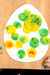 Easter concept. the child places colored plasticine noodles on an egg-shaped paper . children DIY toys for home ideas, child employment, fine motor skills, ergotherapy, sensory therapy