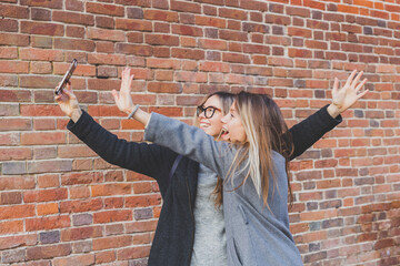 Two hipster girlfriends taking a self photo for social networks in urban city background - friendship concept.