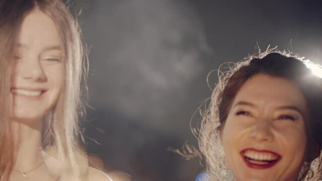 Asian girl and group young college student friends lit light sparkler in hand fireworks, sing and dance together. Woman on Party with people, love friendship relationship and celebration concept.