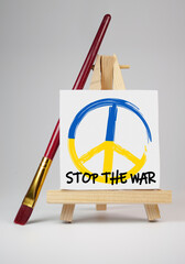 Easel with peace symbol and message stop the war