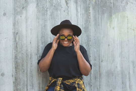 Close-up portrait of stylish young African American girl with curly hair in fashionable sunglasses in urban - summer hipster photos with instagram style