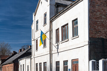 Naklejka premium An old house with the Ukrainian flag. National flag of Ukraine waving in the wind in sunny day.