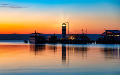 Fototapeta na wymiar Podersdorf, Austria, lighthouse. Passenger ships at pier during beautiful sunset