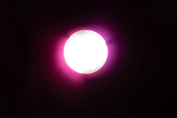 Flat round red chandelier against the background of a stretch ceiling, interiors and electric lighting, consecration