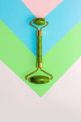 Facial massage jade roller on abstract paper background.