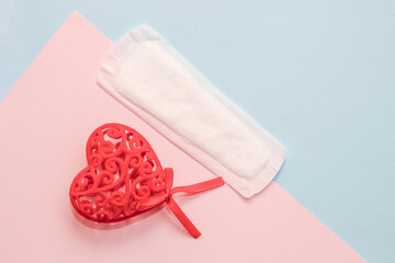Menstrual sanitary napkins supplies with red heart on paper background.