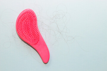 Comb plastic roses with fallen hair on paper background.