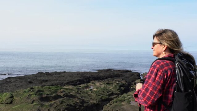 Enjoying a coastal hike.  An affordable short holiday or break. A woman hiking along a rugged sea coast on a sunny day.