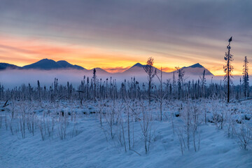 A colorful Alaskan Mountain Range on the Kenai Peninsula at Sunrise with brilliant sky colors is a...
