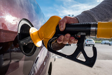Mão a segurar a bomba de combustível para reabastecer o carro no posto de gasolina 