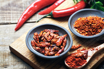 Red chilli peppers raw and powdered.Variety of red hot chilli peppers raw and dried in powder served on wooden table. Red chilli peppers closeup.