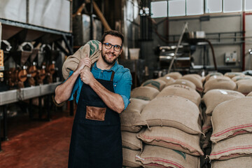 Young man carries sacks of coffee in the coffee factory.