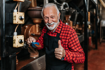 Mature man is working in coffee roasting shop.