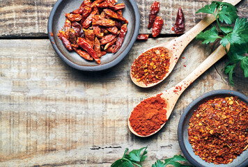 Red chilli peppers raw and powdered.Variety of red hot chilli peppers raw and dried in powder served on wooden table. Red chilli peppers closeup.