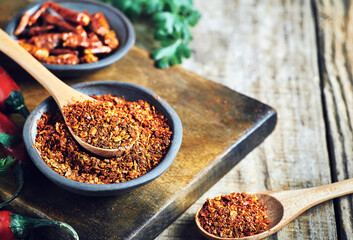Red chilli peppers raw and powdered.Variety of red hot chilli peppers raw and dried in powder served on wooden table. Red chilli peppers closeup.