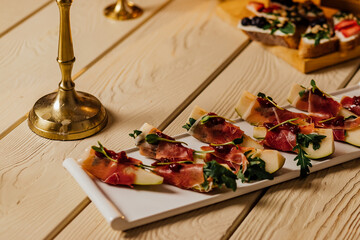 Prosciutto with pear and basil on a black stone plate. Jamon. Italian antipasto. Top view.