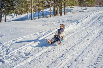 Happy woman having fun during rolling down the mountain slope on sled. Winter sports with snow....