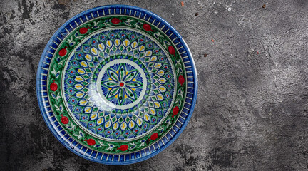 hand painted blue ceramic dish, traditional Uzbek utensils dishes, bowl, plates with national floral ornament on dark background, Long banner format. top view