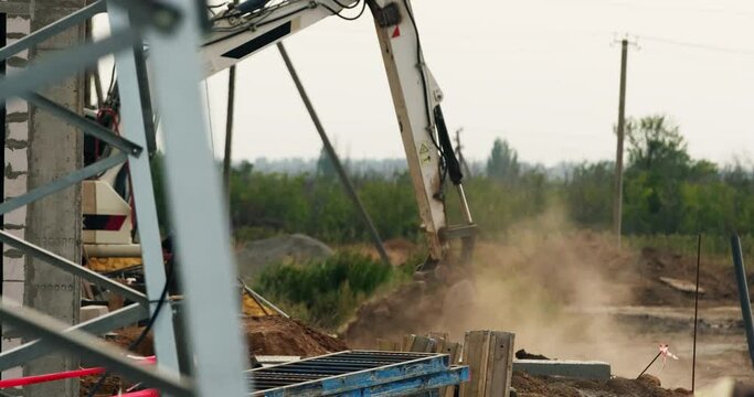 The excavator uses a bucket to collect earth and create trenches. Construction machinery works at a construction site.