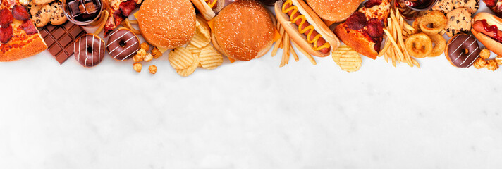 Junk food top border over a white marble banner background. Selection of take out and fast foods....