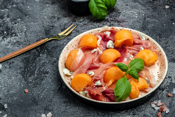 Summer appetizer with sweet melon and prosciutto and basil. Antipasti, Traditional Spanish and Italian appetizer. Top view on white stone table, Long banner format. top view