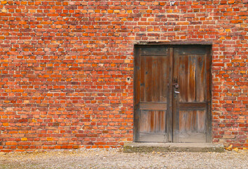 Puerta de madera vieja en una pared de ladrillos. Fondo de escritorio rojo y rústico.