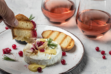 French cuisine. Baked camembert cheese with cranberries and basil leaves, wine on a light...