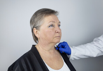 An elderly woman at the reception of a facial plastic surgeon. Consultation on the removal of age...