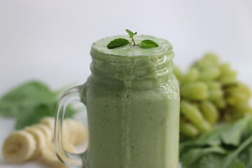 Green smoothie made of frozen green grapes, fresh baby spinach, bananas and almond milk. Served in mason jar