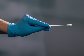 Close up of hand in medical gloves handling a smear test or swab test for corona detection