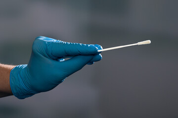 Close up of hand in medical gloves handling a smear test or swab test for corona detection
