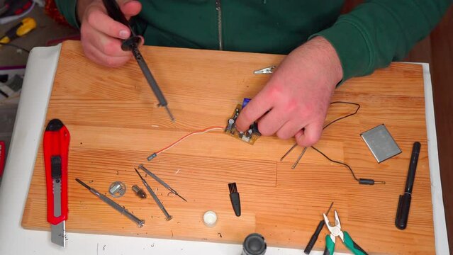 Closeup view of simple electric circuit, breadboard with electrical components, diode, resistors, soldering electrical colored cables and wires. Hand soldering station. Electronic parts