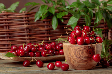 Red sweet cherry in a wooden bowl on a wooden table.