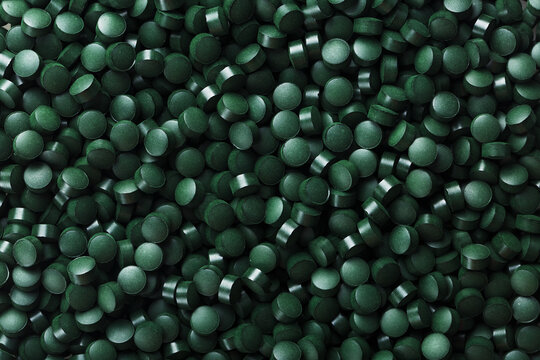 Dark Green round tablets of organic spirulina as a texture