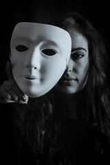 Be authentic and true concept - Black and white portrait of a beautiful young woman with long hair taking off her mask