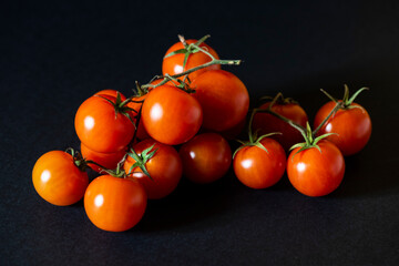 Cherry tomatoes with green stems on black background