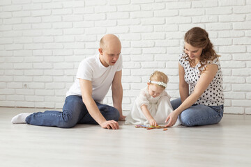 Baby child with hearing aids and cochlear implants plays with parents on floor. Deaf and rehabilitation concept