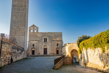 The village of Tarquinia, Viterbo, Lazio, Italy - The tower and facade of the Church of Santa Maria in Castello, in Romanesque style. Three arched doors, the mullioned window and the bell tower.