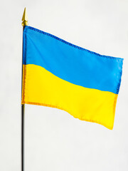 Close-up. On a white background the state flag of Ukraine. Identification of statehood, patriotism, freedom, independence. Bright colours. There are no people in the photo.