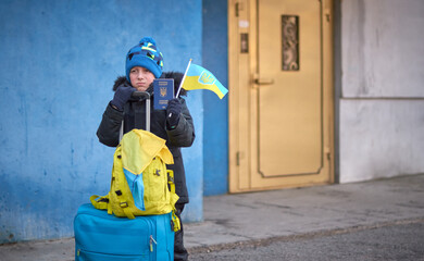 Evacuation of civilians, sad child with the flag of Ukraine. Refugee family from Ukraine crossing...