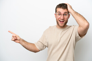 Young caucasian man isolated on white background surprised and pointing finger to the side