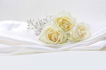 Beige rose flower bouquet on white silk copy space background.