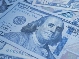 American paper money. A $100 bill with focus on eyes of Benjamin Franklin. US banknotes close-up. Business economy and the USA dollar. Blue tinted background. Macro