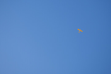 Light aircraft flies in the clear blue sky. Background or backdrop. Yellow small plane. General aviation. Air sports and tourism